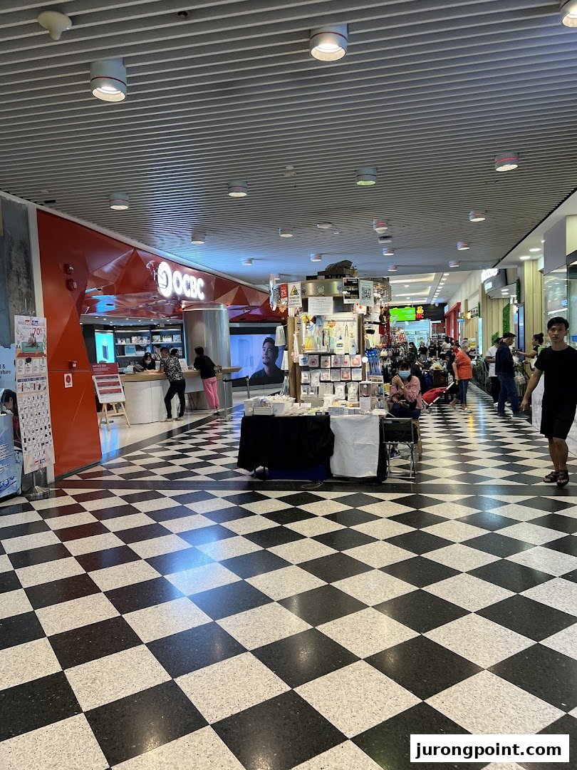 The OCBC Bank branch entrance at Jurong Point, featuring a distinctive checkered floor and mall activity.