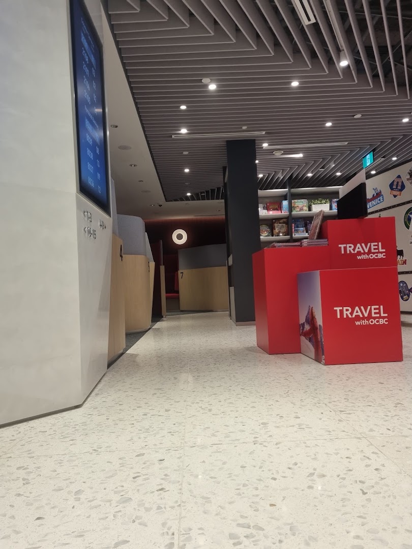 Interior view of OCBC Bank, featuring a waiting area, digital queue display, and 'Travel with OCBC' promotional stands.