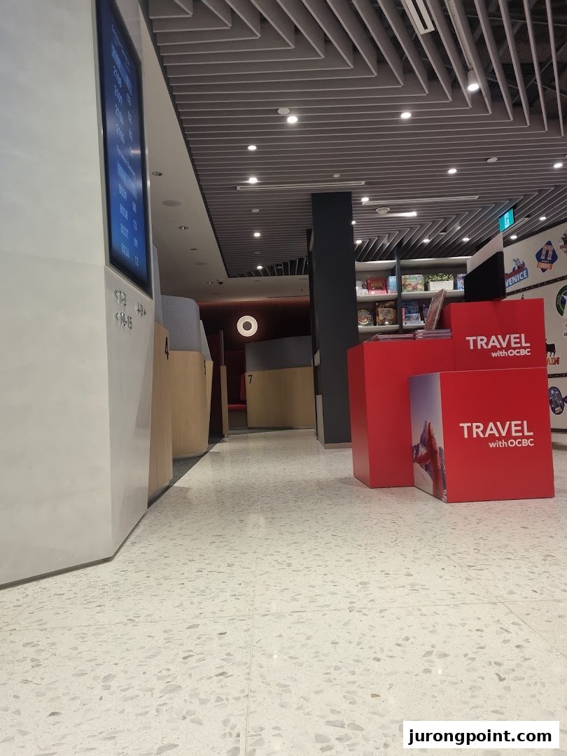 Interior view of OCBC Bank, featuring a waiting area, digital queue display, and 'Travel with OCBC' promotional stands.