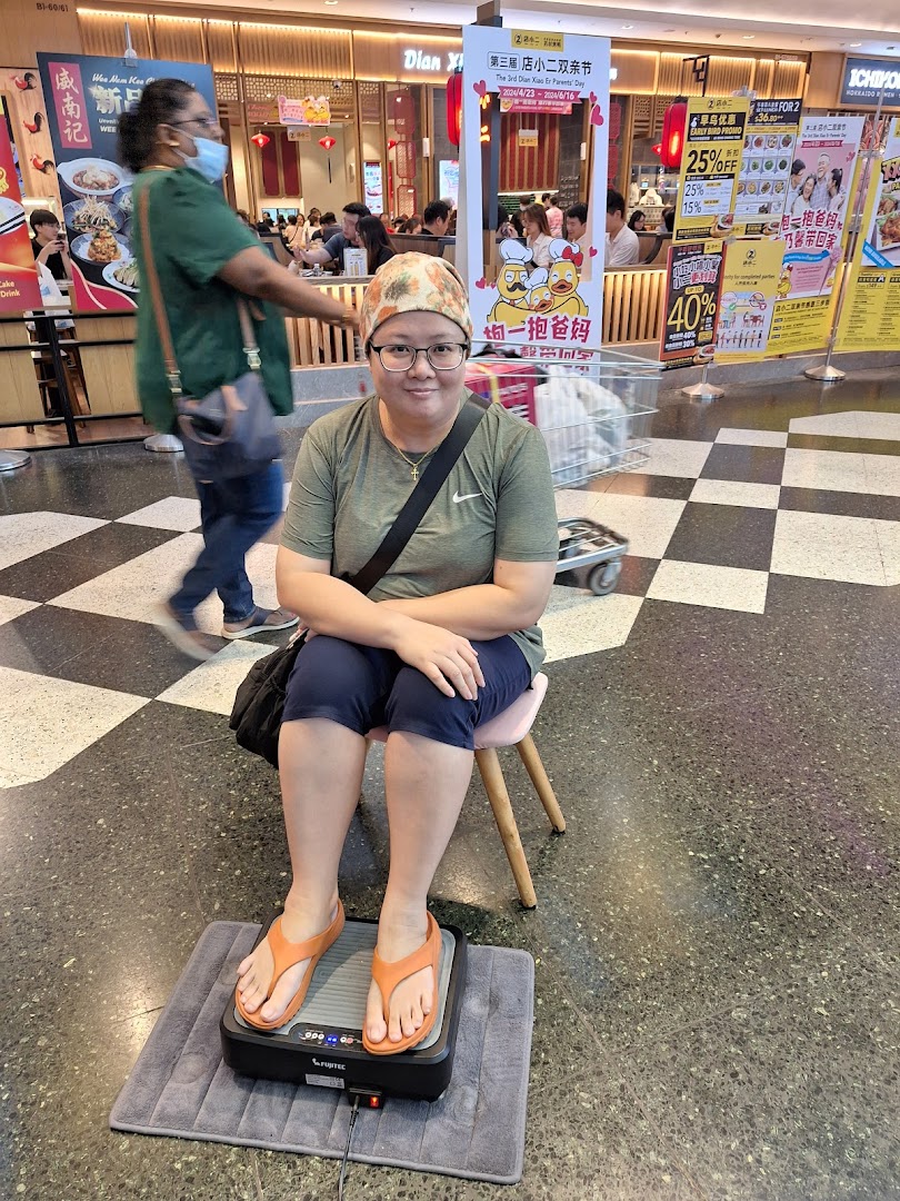 A person comfortably testing a foot massager in a mall aisle, showcasing a wellness product.