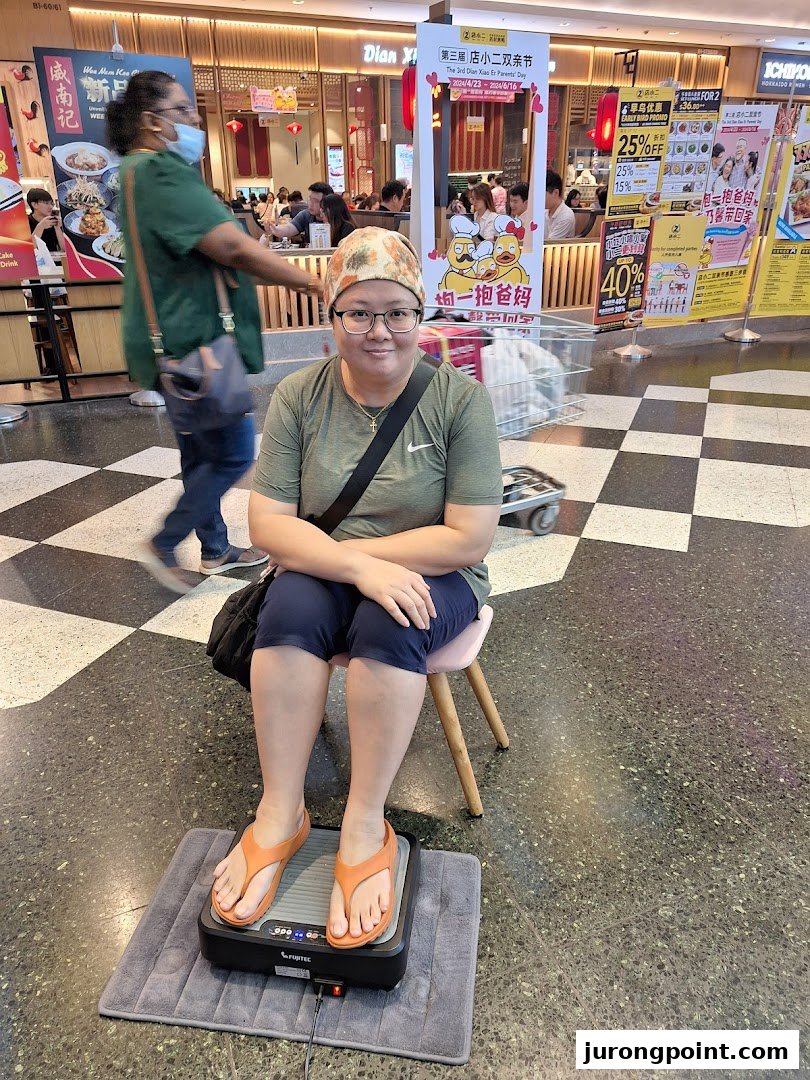 A person comfortably testing a foot massager in a mall aisle, showcasing a wellness product.