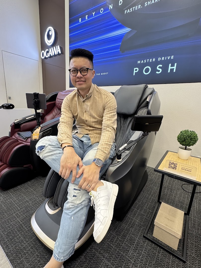 A man comfortably seated on a premium massage chair inside the OGAWA store, showcasing the product.