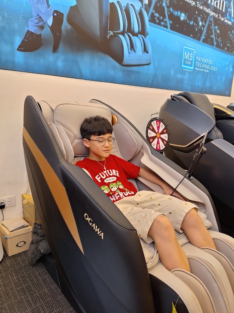 A young person relaxing in an OGAWA massage chair inside the store.