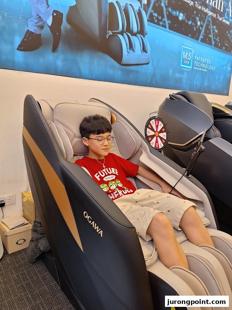 A young person relaxing in an OGAWA massage chair inside the store.