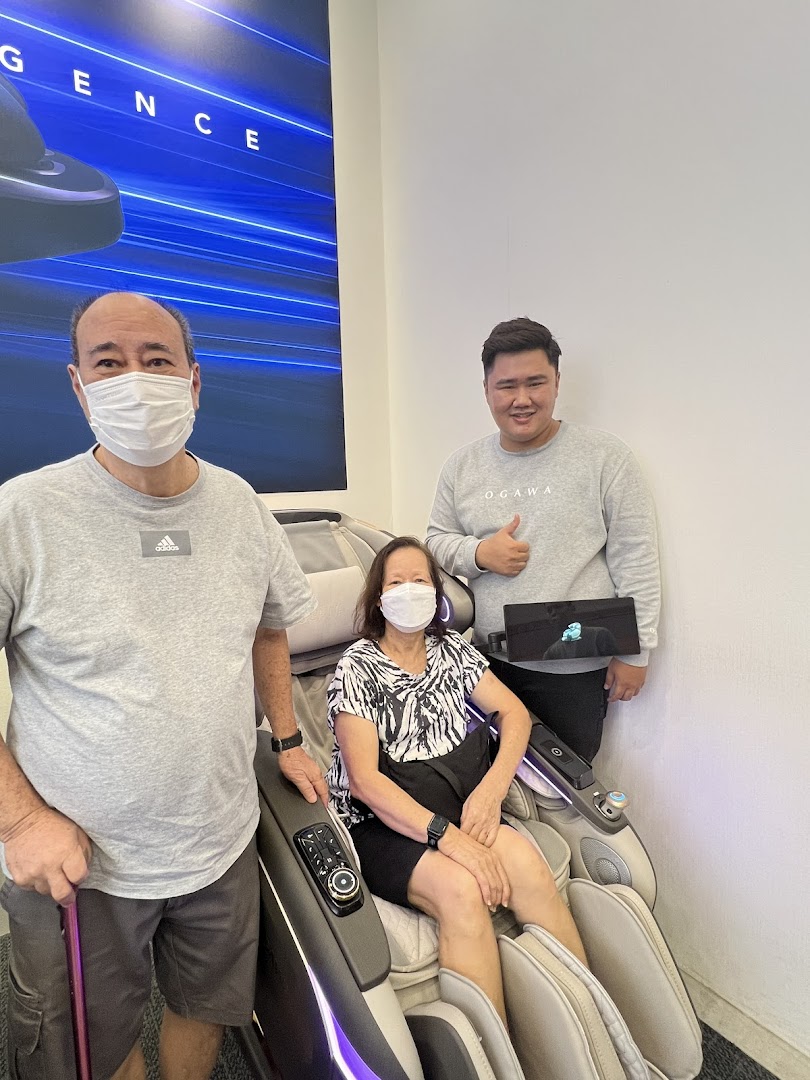 Customers and staff interacting with a massage chair inside the Ogawa store.