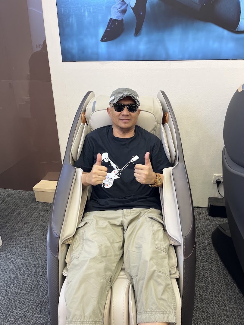 A man happily testing a massage chair inside the OGAWA store, giving a thumbs-up.