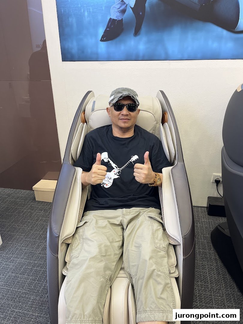 A man happily testing a massage chair inside the OGAWA store, giving a thumbs-up.