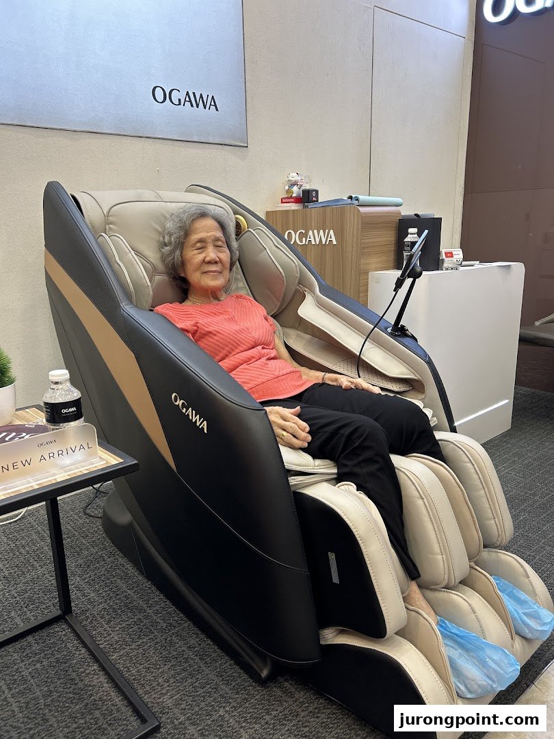 An elderly woman comfortably testing a luxurious massage chair inside an OGAWA retail store.