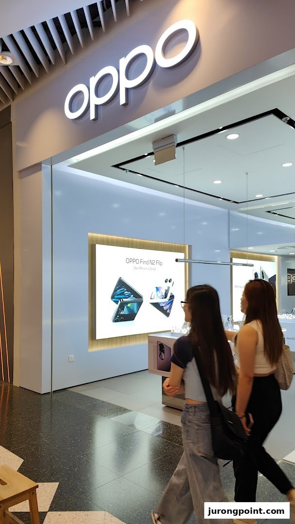 The entrance of an OPPO Concept Store featuring its prominent logo and an interior display with people walking past.