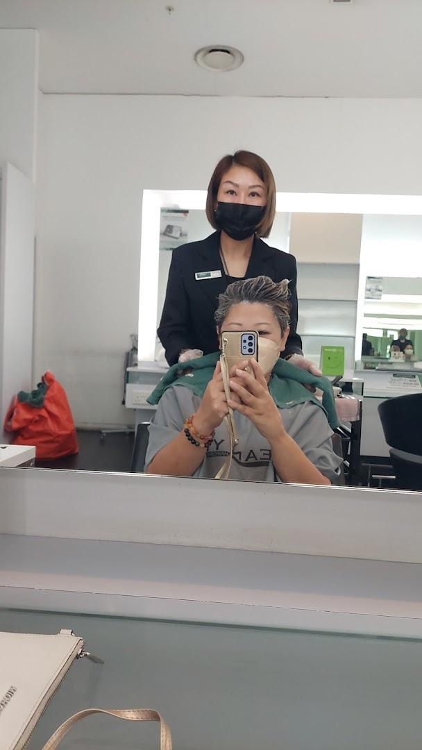 A customer receives a hair treatment from a staff member in a modern hair salon.