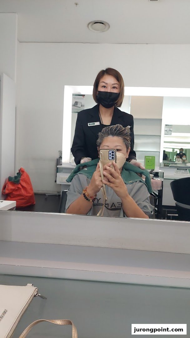 A customer receives a hair treatment from a staff member in a modern hair salon.