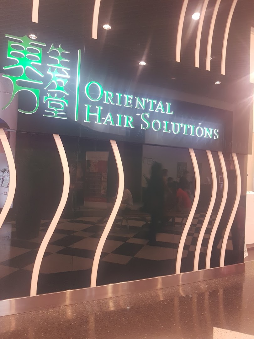 The illuminated shop front of Oriental Hair Solutions, featuring a sleek black facade with white wavy accents.