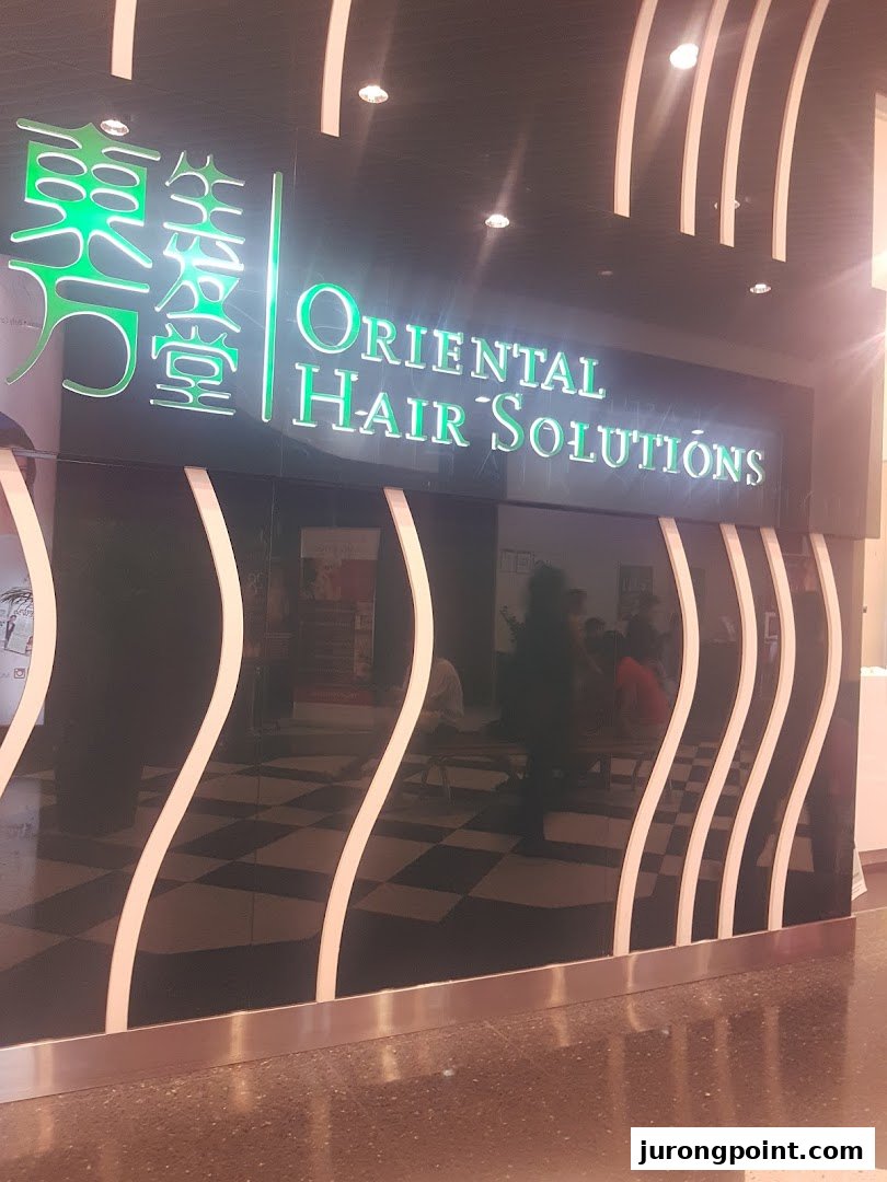 The illuminated shop front of Oriental Hair Solutions, featuring a sleek black facade with white wavy accents.