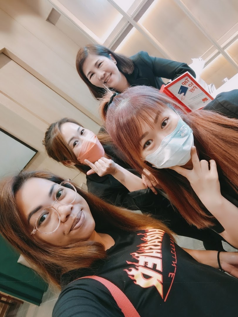 Four smiling individuals, likely staff or customers, inside Oriental Hair Solutions.