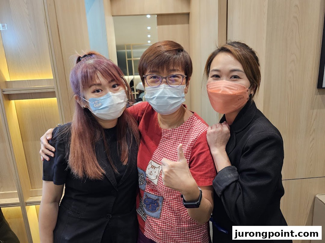 Three smiling women, likely staff or a customer and staff, pose together inside Oriental Hair Solutions.