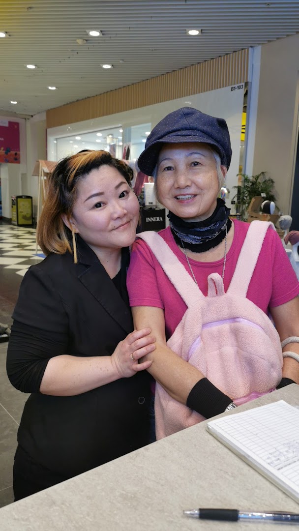 Two women, one possibly a staff member, smiling at the counter of Oriental Hair Solutions.