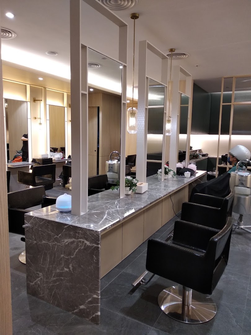 A modern hair salon interior featuring multiple styling stations with marble countertops and comfortable chairs.