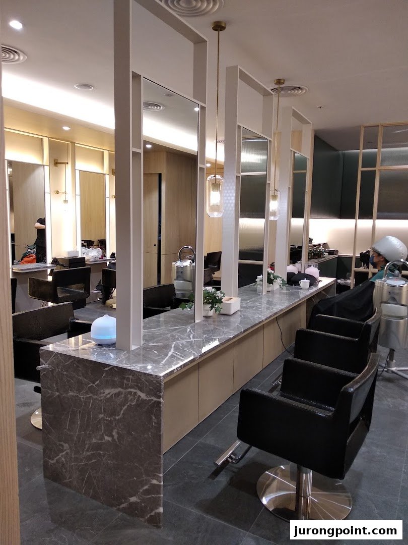 A modern hair salon interior featuring multiple styling stations with marble countertops and comfortable chairs.