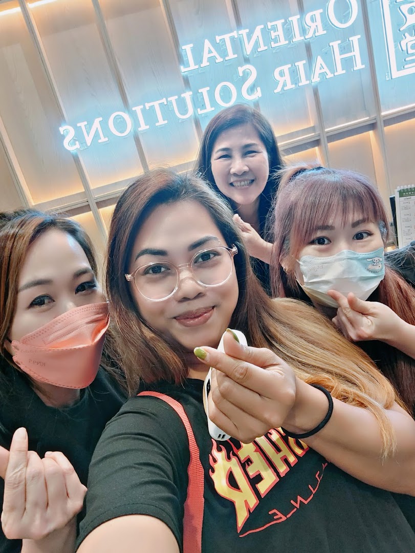 Four smiling women, likely staff or customers, pose for a selfie inside Oriental Hair Solutions.