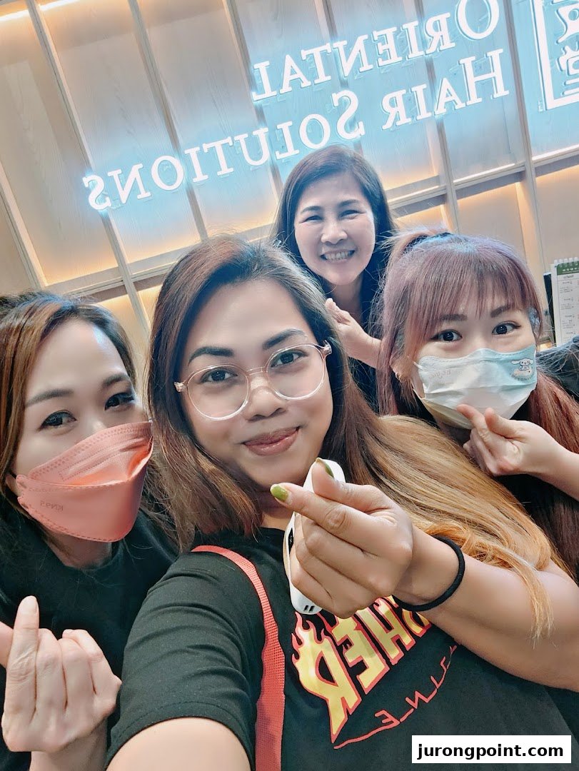 Four smiling women, likely staff or customers, pose for a selfie inside Oriental Hair Solutions.
