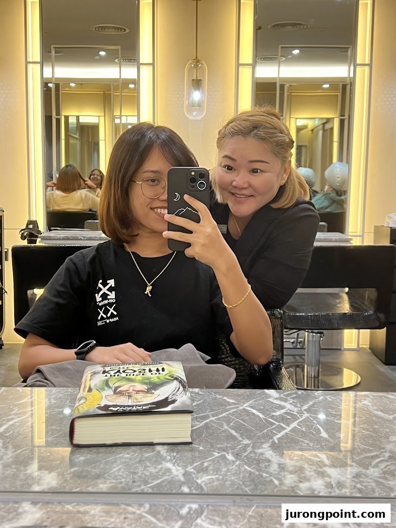 A customer and staff member smiling for a selfie inside Oriental Hair Solutions salon.
