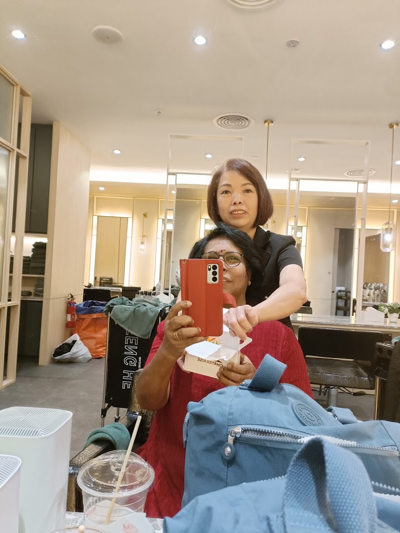 A customer takes a selfie with a staff member inside a modern hair salon.