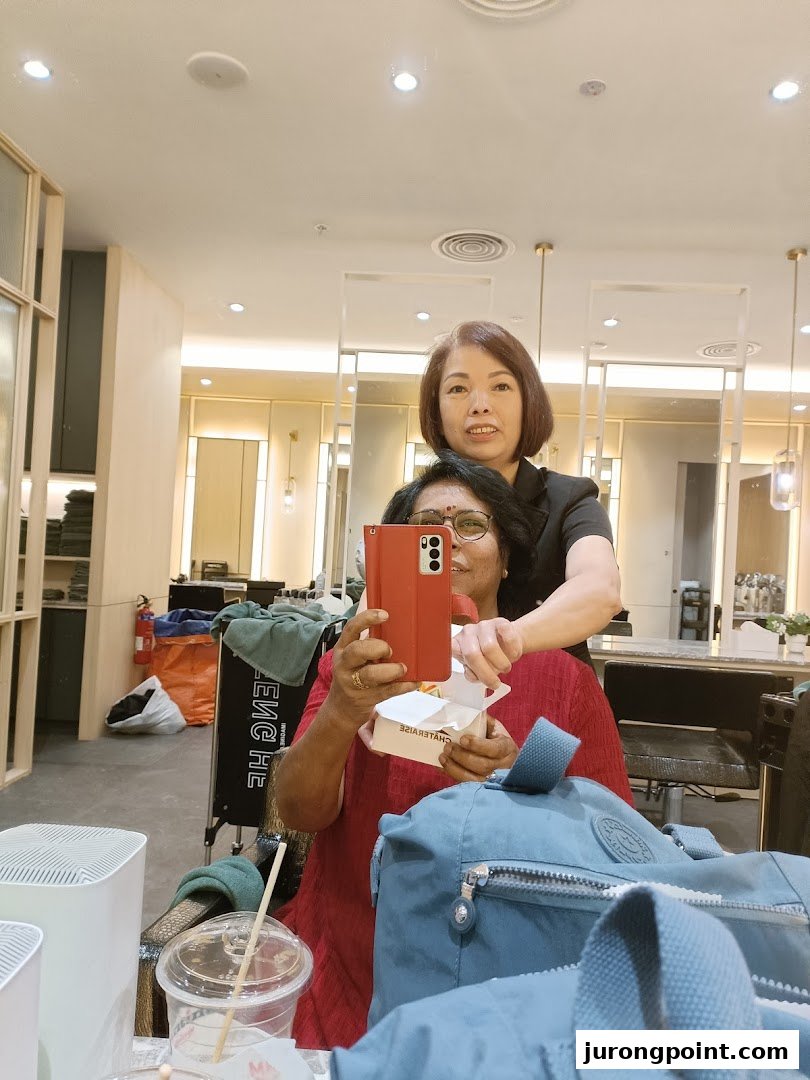 A customer takes a selfie with a staff member inside a modern hair salon.