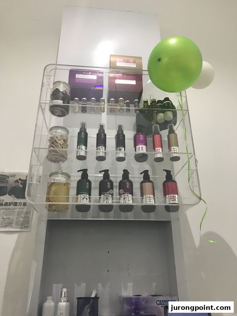 A clear display shelf showcasing various hair care products and traditional ingredients in a salon setting.
