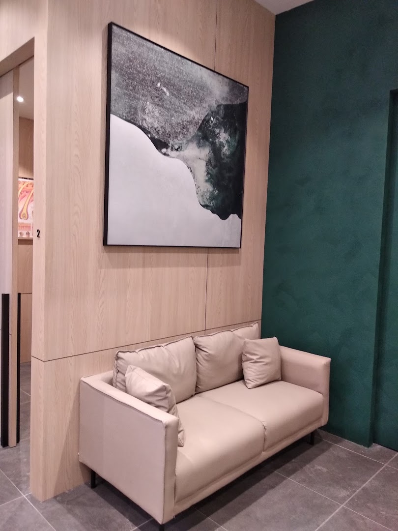 A comfortable waiting area with a beige sofa, modern artwork, and wood paneling at Oriental Hair Solutions.