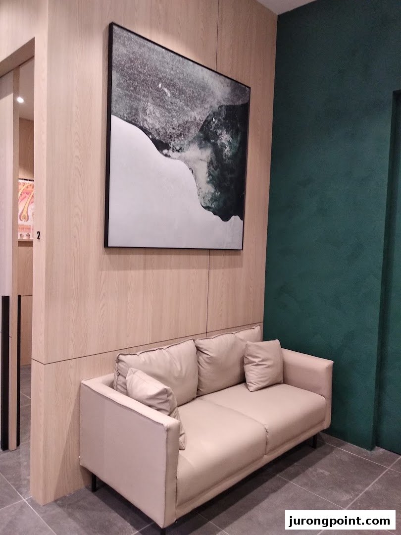 A comfortable waiting area with a beige sofa, modern artwork, and wood paneling at Oriental Hair Solutions.