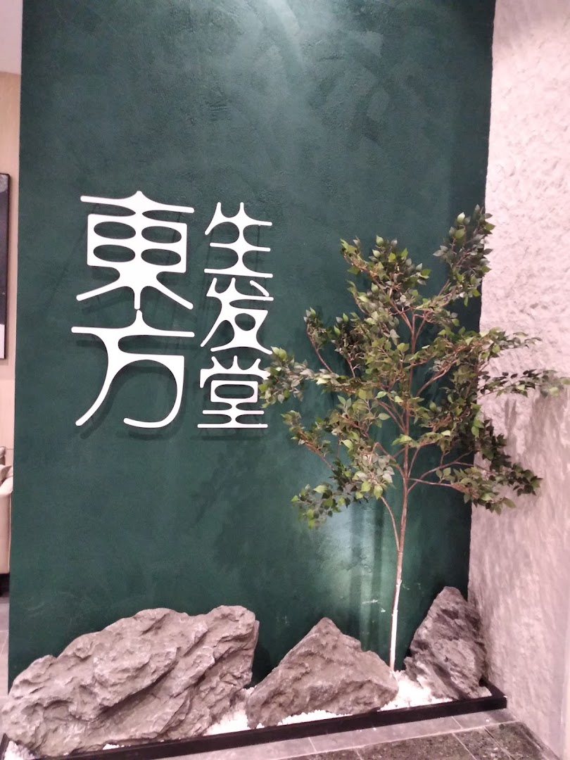 The shop front of Oriental Hair Solutions features a dark green wall with white stylized Chinese characters and natural rock and plant decor.