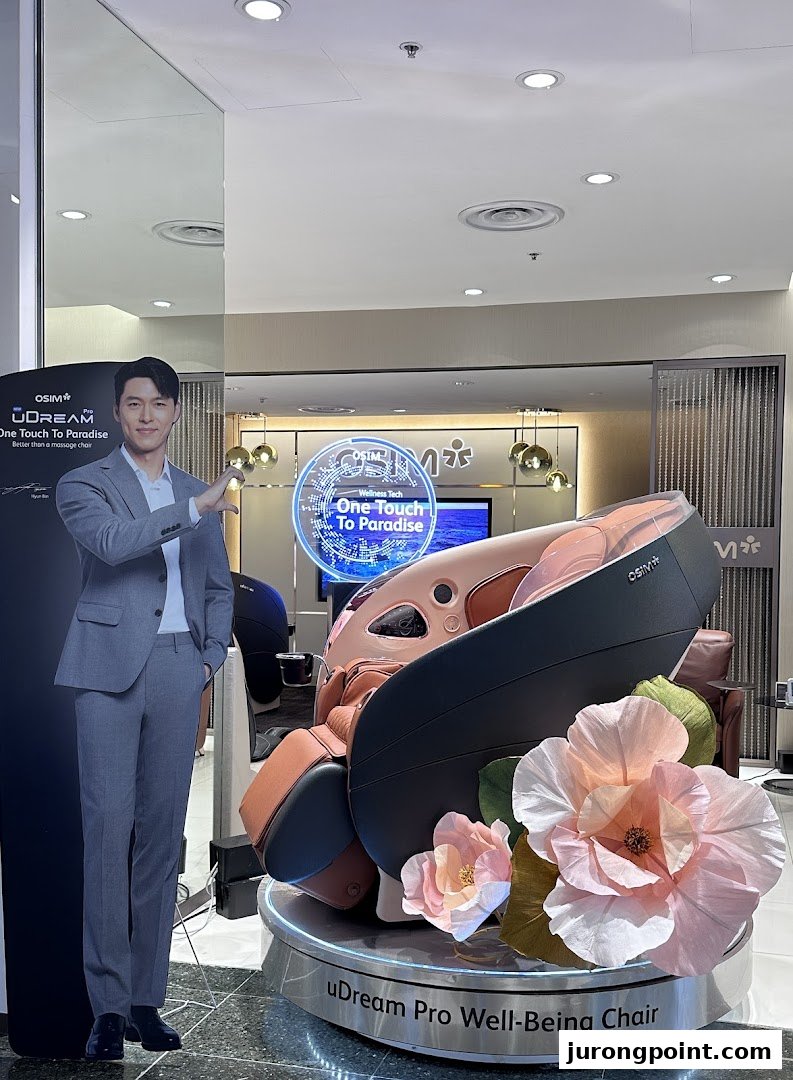 An OSIM uDream Pro Well-Being Chair display with a celebrity cutout and floral decor.
