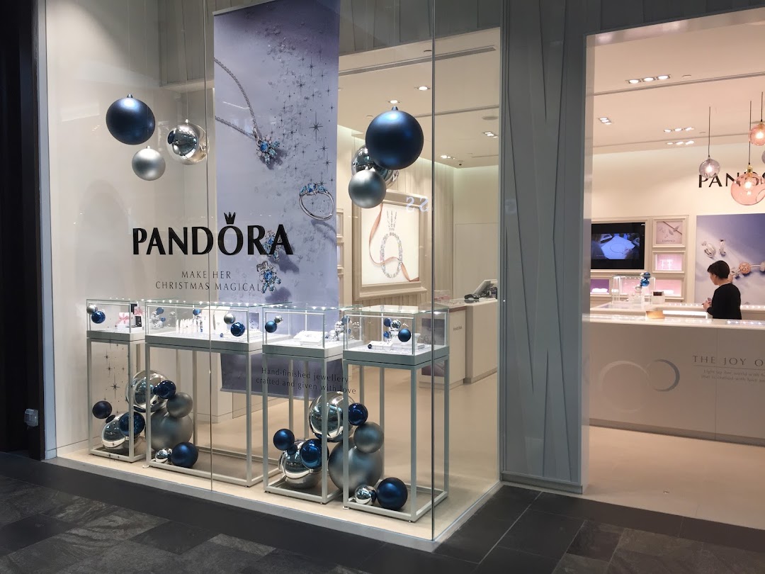 The Pandora shop front features festive displays with jewelry showcases and holiday ornaments.