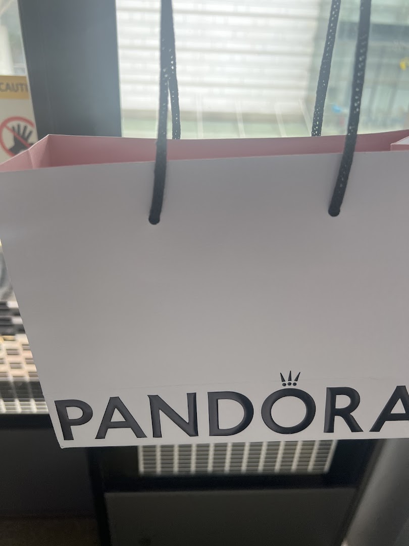 A white Pandora shopping bag with black handles and the brand logo prominently displayed.