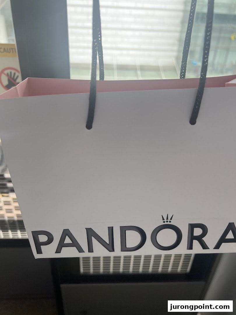 A white Pandora shopping bag with black handles and the brand logo prominently displayed.