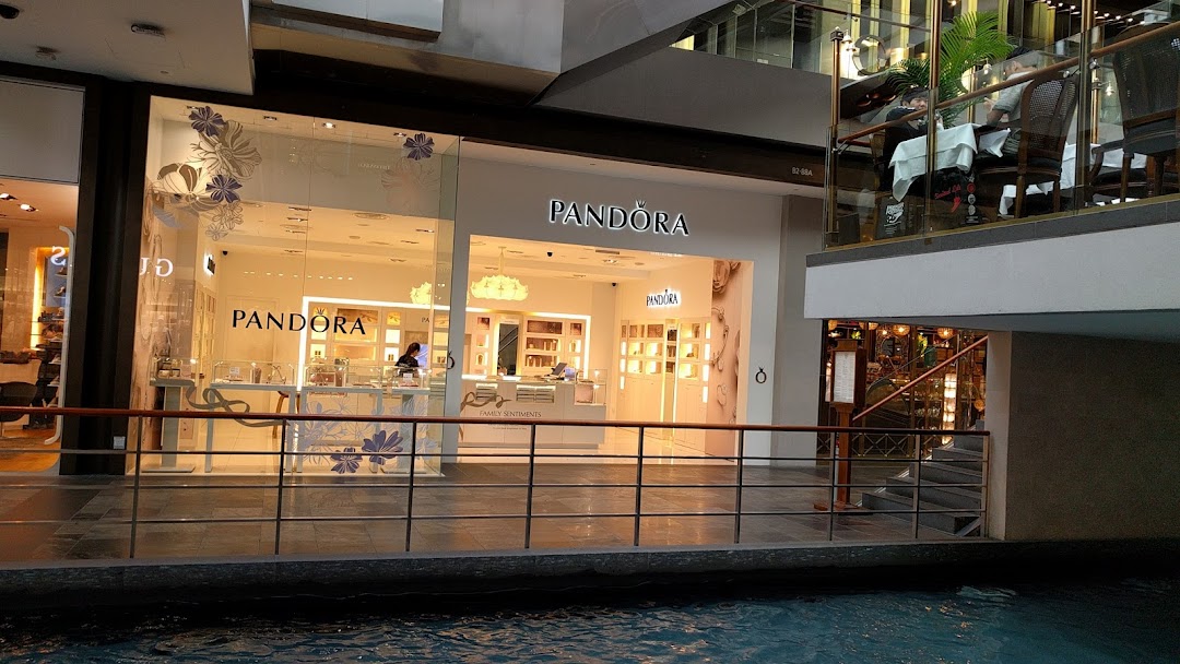 The brightly lit Pandora jewelry shop front with display windows, seen from across an indoor canal.