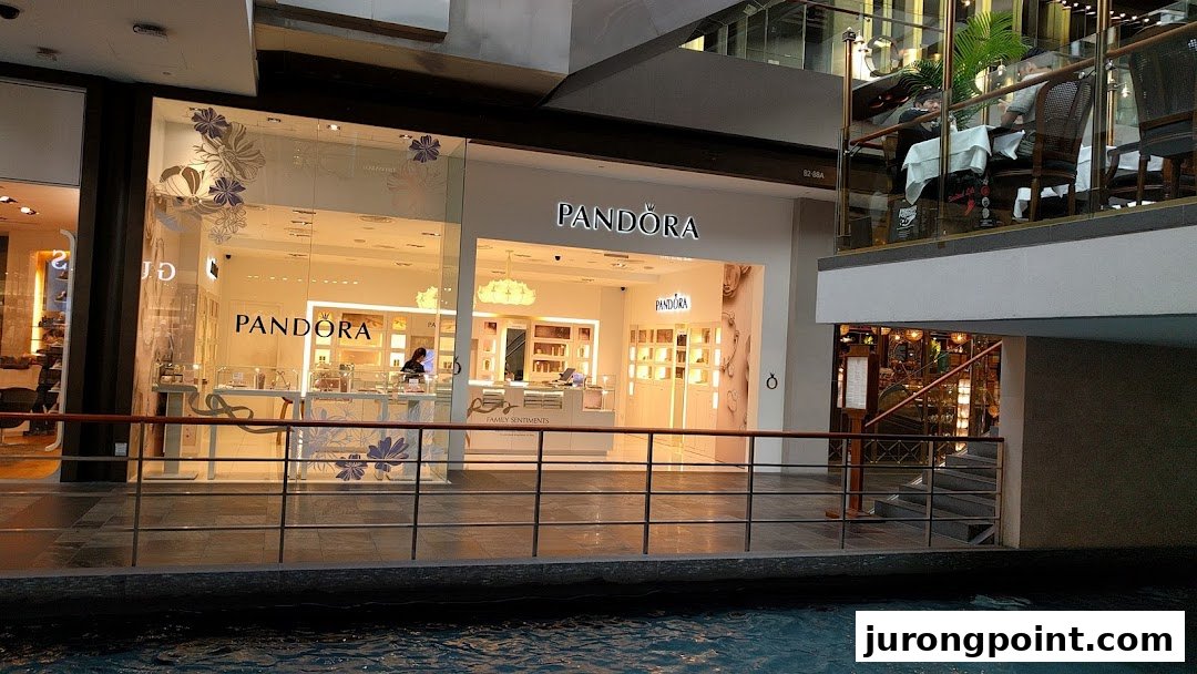 The brightly lit Pandora jewelry shop front with display windows, seen from across an indoor canal.