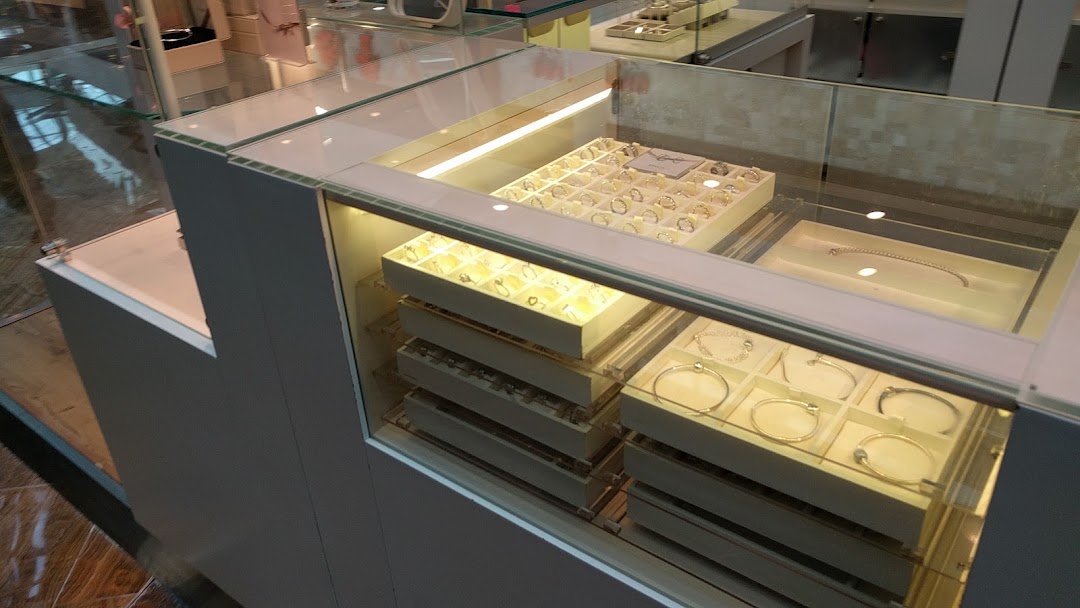A brightly lit glass display case showcasing a variety of Pandora rings and bracelets.