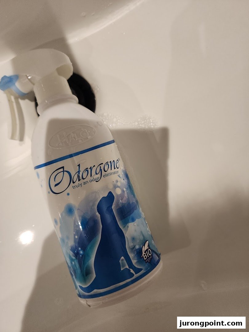 A bottle of Odorgone pet odor eliminator spray with a dog silhouette design in a white sink.