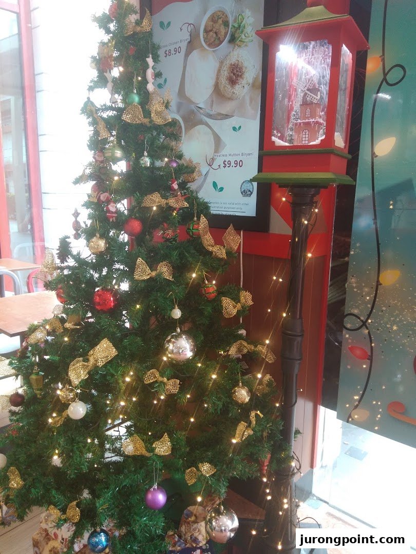 A festive Christmas tree and decorative lamp post adorn the shop interior, with a food menu poster in the background.