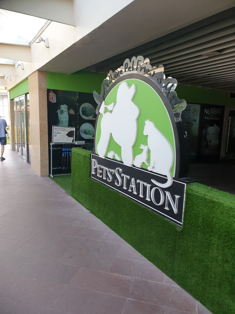 The entrance of Pets Station, featuring a large pet-themed sign and artificial grass decor.