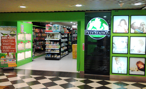 The Pets Station shop front features a bright green entrance, displaying pet supplies and a loyalty program.