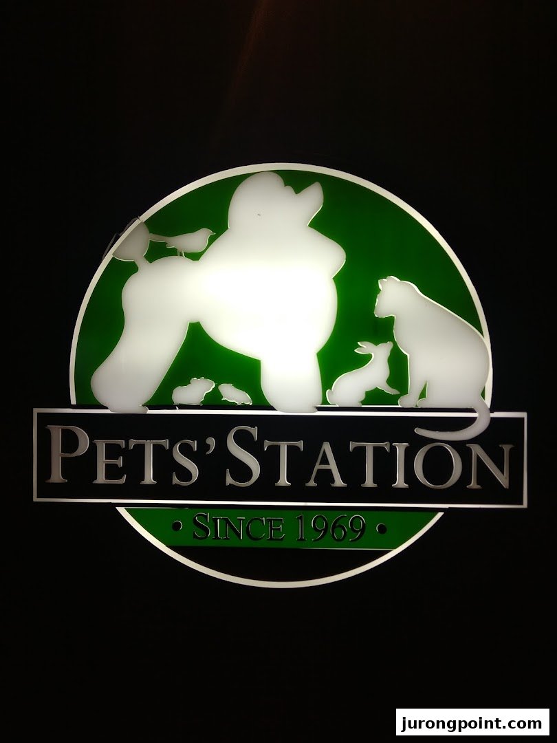 An illuminated Pets' Station logo featuring various pet silhouettes on a green background.