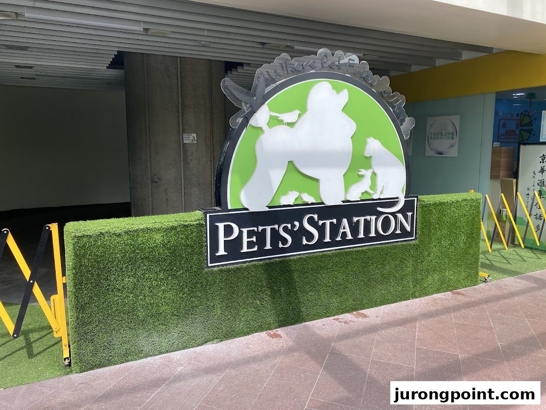 The exterior sign of Pets Station, featuring pet silhouettes and artificial grass landscaping.