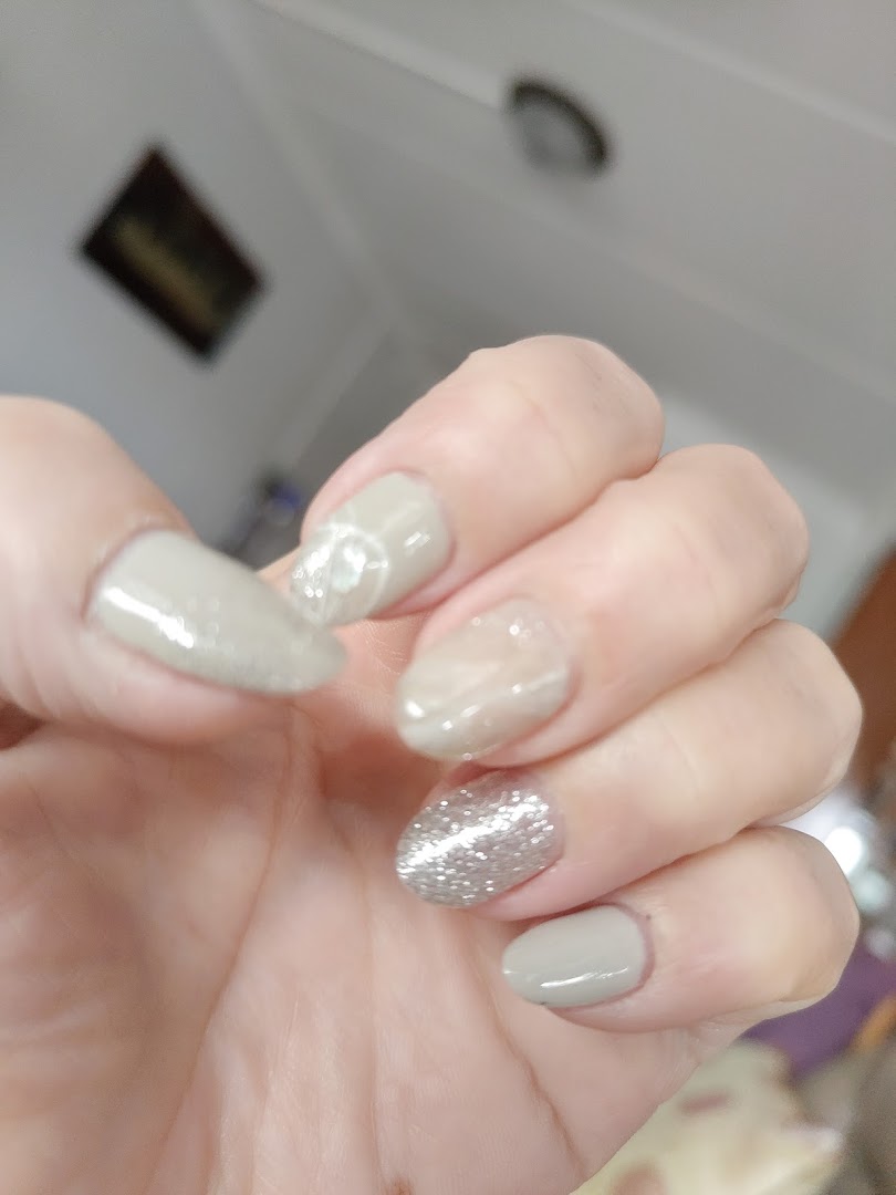 A hand showcasing beautifully manicured nails with a mix of solid, glitter, and marble designs.