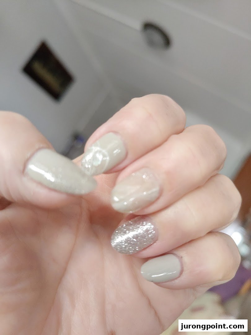 A hand showcasing beautifully manicured nails with a mix of solid, glitter, and marble designs.