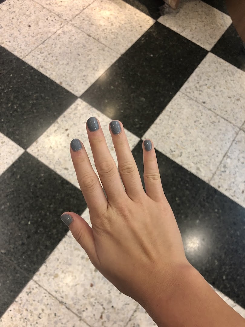 A hand with freshly painted grey nails against a black and white checkered floor.
