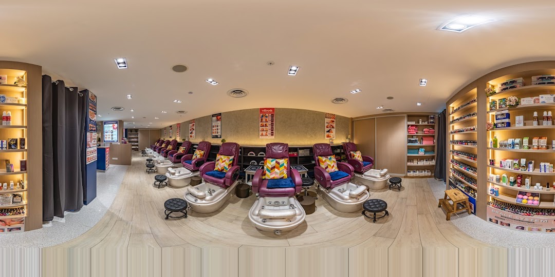 Interior view of a modern nail spa featuring multiple comfortable pedicure stations and extensive product displays.