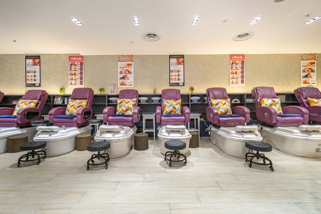 A row of comfortable purple pedicure chairs with foot spas in a modern nail salon.