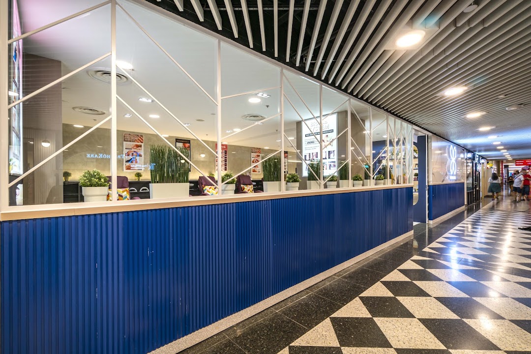 The vibrant blue and white facade of Pixie Nail Spa, seen from the mall corridor, inviting relaxation.